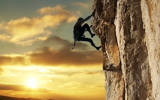 Pessoa escalando montanha ao pôr do sol, simbolizando a agilidade e superação da complexidade na jornada para a nuvem privada com VCF.