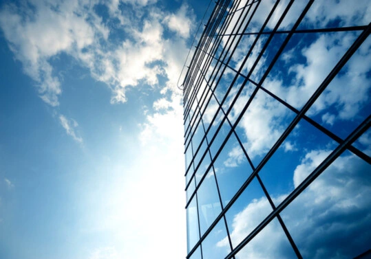 Edifício corporativo moderno refletindo o céu, simbolizando a viabilidade e o desempenho enterprise da solução VMware VVF para nuvem privada.